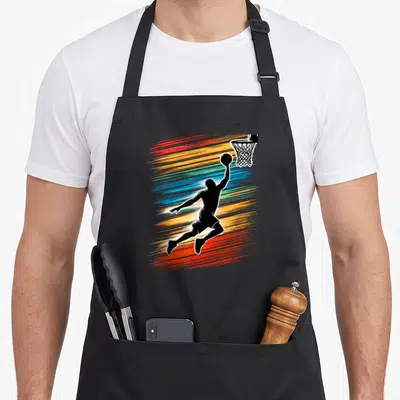 Tablier de cuisine noir avec une illustration d'un basketteur effectuant un dunk sur un fond de traits multicolores dynamiques.