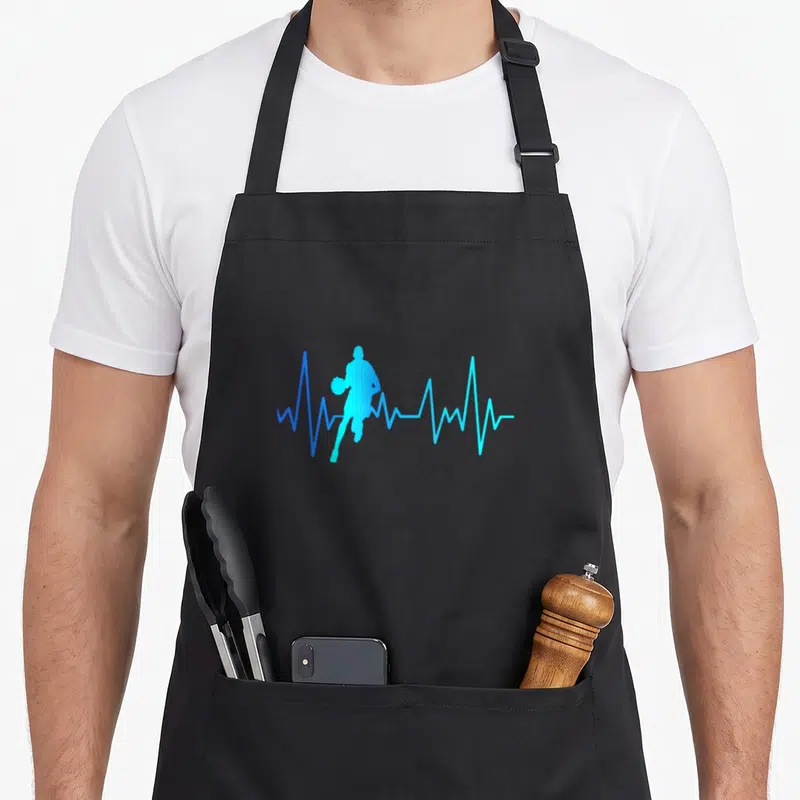 Tablier de cuisine noir avec silhouette bleue d'un joueur de basket-ball sur fond de ligne de rythme cardiaque.