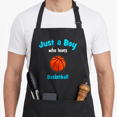Tablier de cuisine noir avec un ballon de basket orange et le texte Just a Boy who loves Basketball en bleu et blanc.