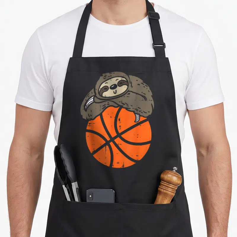 Tablier de cuisine noir avec un sloth marron blotti sur un ballon de basket orange