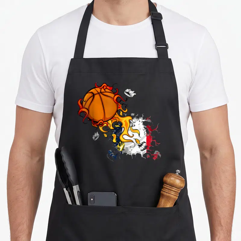 Tablier de cuisine noir avec une balle de basket enflammée traversant un drapeau tricolore aux couleurs vives.