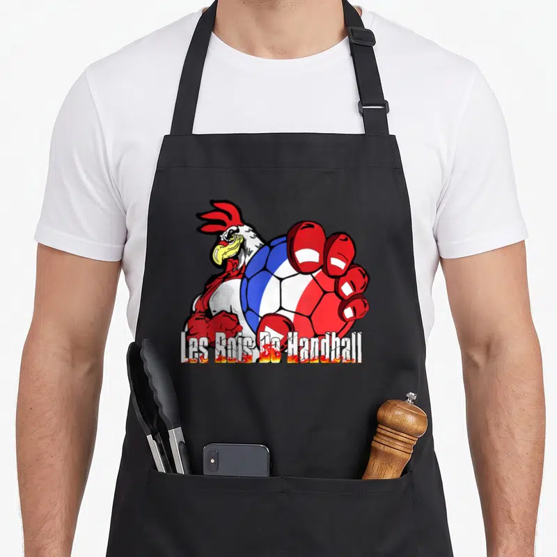 Tablier de cuisine noir avec un coq musclé tenant un ballon handball aux couleurs de la France et le texte Les Rois De Handball.
