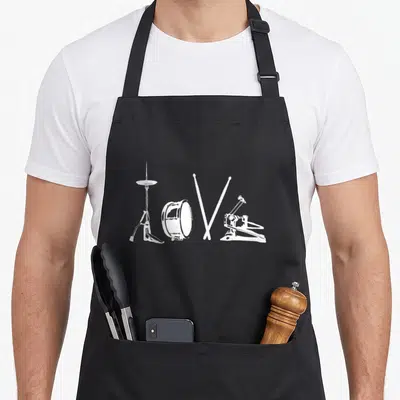 Tablier de cuisine noir avec illustration blanche représentant un cymbalier, un tambour, deux baguettes croisées et une pédale de basse forming le mot Love.