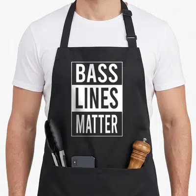 Tablier de cuisine noir avec inscription graphique blanche et grise « Bass Lines Matter » en typographie moderne.