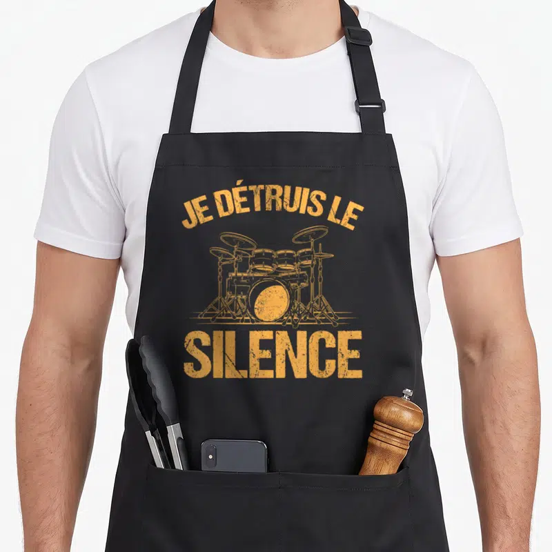 Tablier de cuisine noir avec illustration orange d'un set de batterie et le texte Je détruis le silence imprimé en lettres capitales.