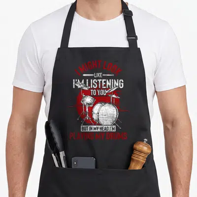 Tablier de cuisine noir avec illustration de batterie rouge et texte blanc sur fond circulaire.