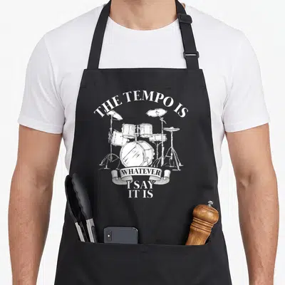 Tablier de cuisine noir avec illustration blanche d'un kit de batterie et texte humoristique en anglais.