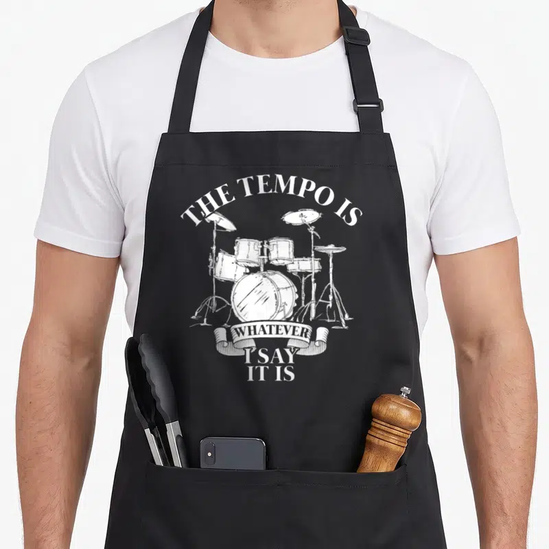 Tablier de cuisine noir avec illustration blanche d'un kit de batterie et texte humoristique en anglais.