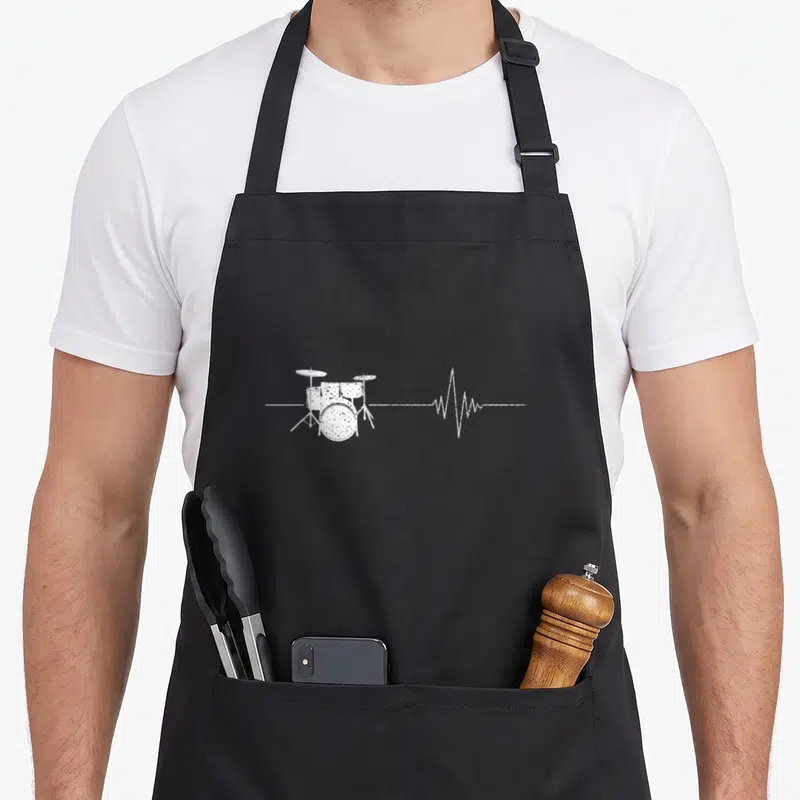 Tablier de cuisine noir avec illustration blanche d'une batterie et d'une ligne d'onde sonore stylisée.