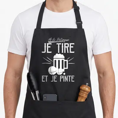 Tablier de cuisine noir avec inscription blanche Je Tire Et Je Pinte au-dessus d'une bière et de deux boules de pétanque.