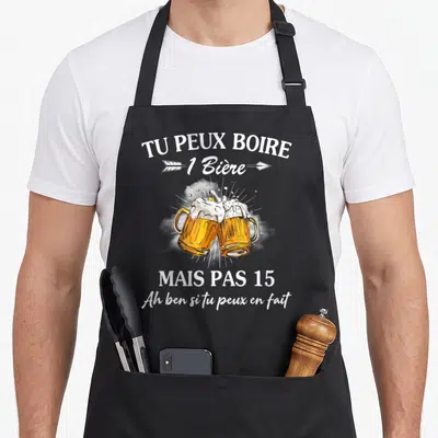 Tablier de cuisine noir avec deux verres de bière qui se touchent et un texte humoristique blanc imprimé au centre.