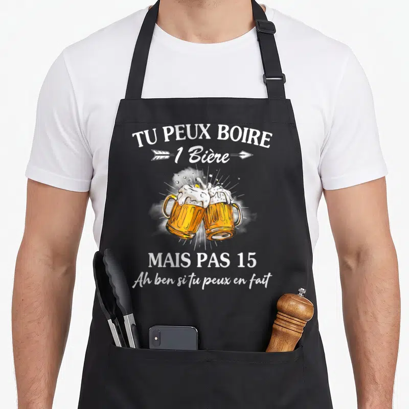 Tablier de cuisine noir avec deux verres de bière qui se touchent et un texte humoristique blanc imprimé au centre.