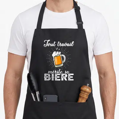 Tablier de cuisine noir avec inscription tout travail mérite sa bière et illustration de mug doré à la mousse blanche.