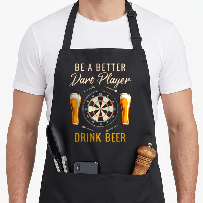 Tablier de cuisine noir avec illustration de fléchettes, cible et deux verres de bière dorée.
