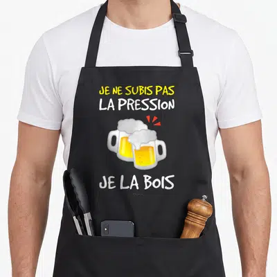 Tablier de cuisine noir avec deux verres de bière et le texte Je ne subis pas la pression je la bois imprimé en jaune et blanc.