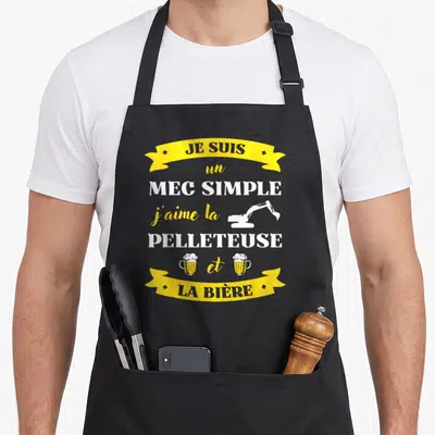 Tablier de cuisine noir avec inscription jaune et blanche surmec simple pelleteuse et bière illustrée.