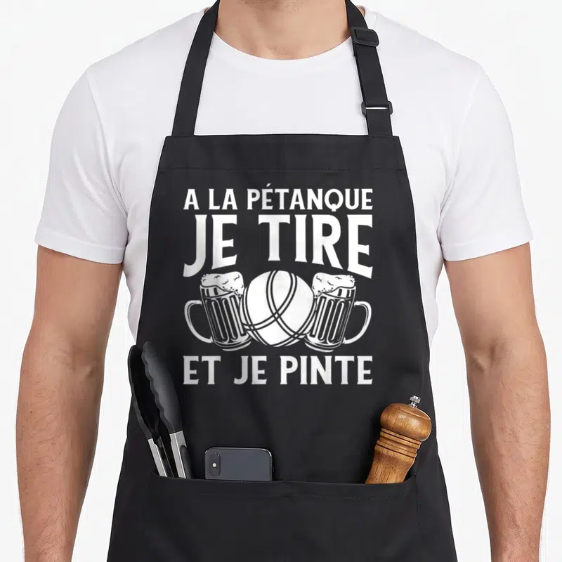 Tablier de cuisine noir avec une boule de pétanque entre deux verres de bière et du texte blanc humoristique.
