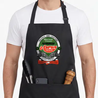 Tablier de cuisine noir avec l'emblème circulaire vert et rouge Aspen Beer Weyland Yutani orné d'épis de céréales.