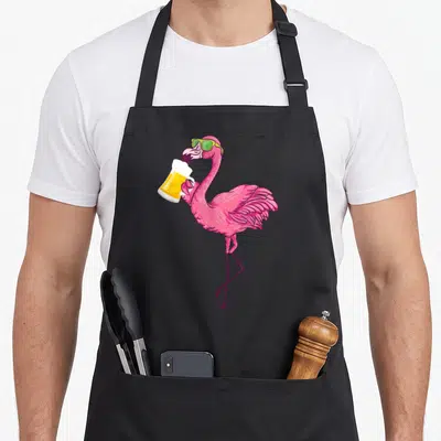 Tablier de cuisine noir avec un flamant rose rose vif buvant une bière dans une coupe en verre.