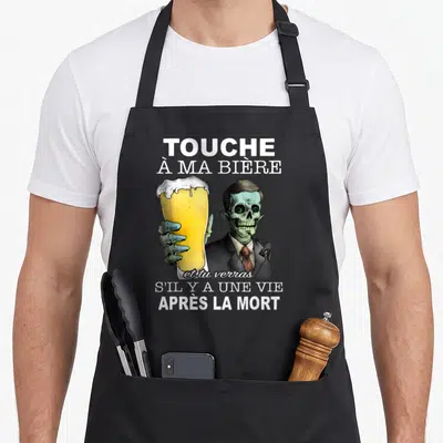 Tablier de cuisine noir avec illustration d'un squelette en costume tenant une grande bière dorée.