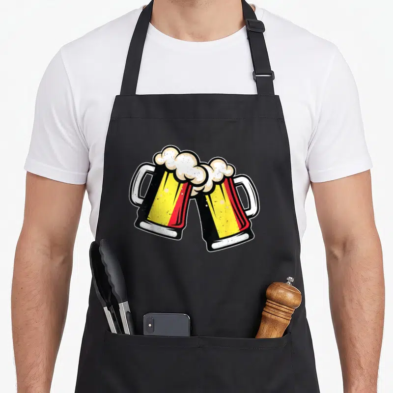 Tablier de cuisine noir avec deux chopes à bière belge jaune rouge et mousse blanche se touchant en toast.