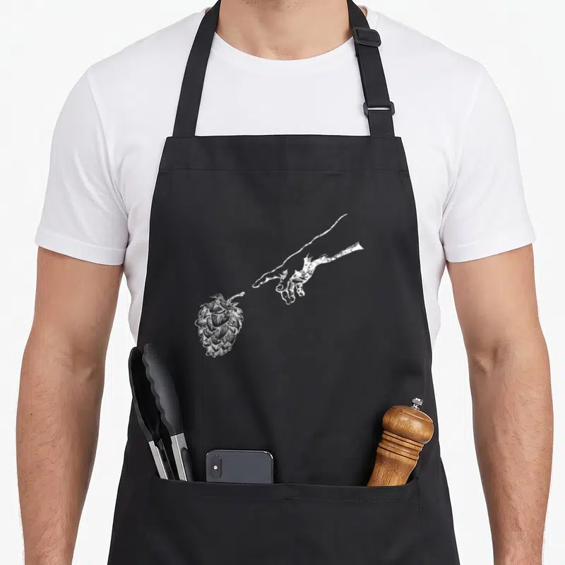 Tablier de cuisine noir avec une illustration blanche d'une main s'étirant vers un houblon détaillé.