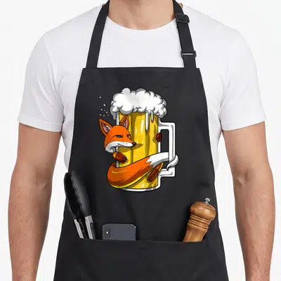 Tablier de cuisine noir avec un renard orange enlaçant une grande chope de bière à la mousse blanche.