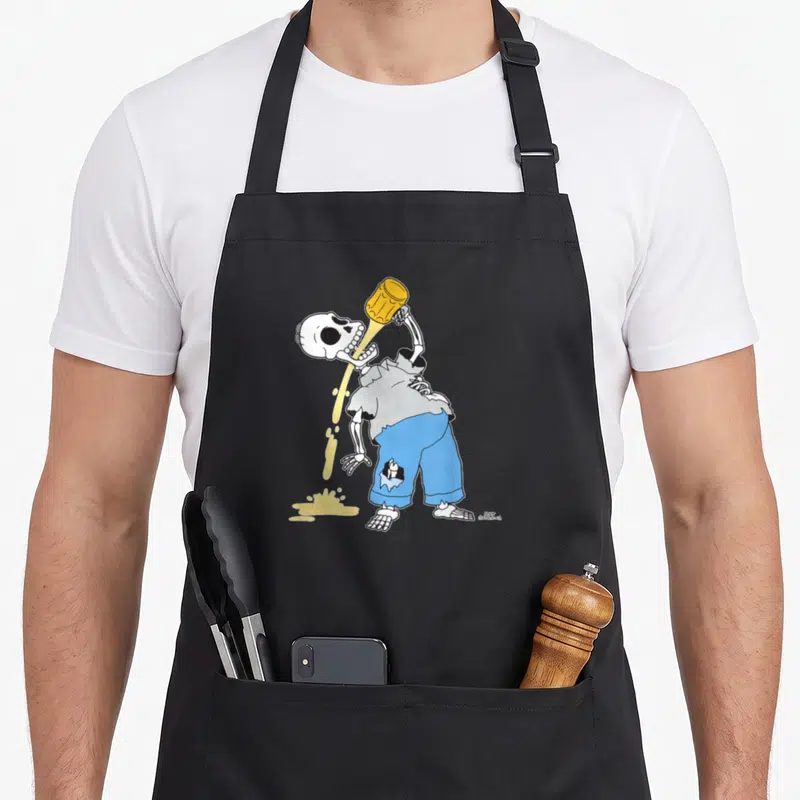 Tablier de cuisine noir avec un squelette en chemise grise et pantalon bleu buvant une bière dorée qui s'écoule sur le sol.