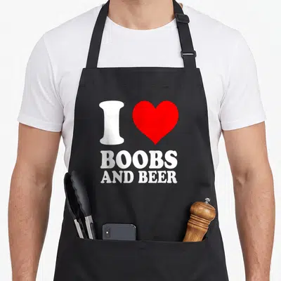 Tablier de cuisine noir avec inscription blanche I Love Boobs and Beer et un cœur rouge vif au centre du design.