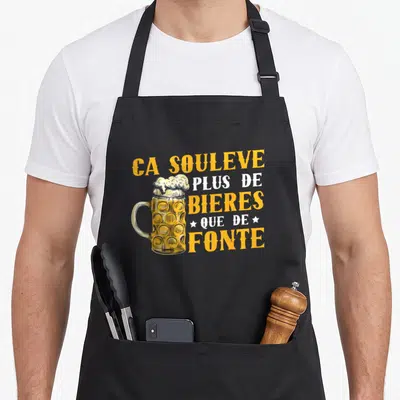 Tablier de cuisine noir avec illustration de mug de bière et texte jaune et blanc humoristique.