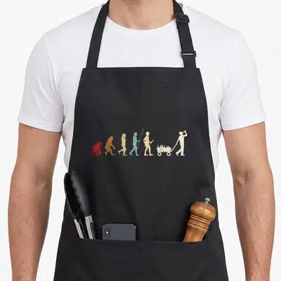 Tablier de cuisine noir avec illustration évolutive colorée d'hommes tirant une charrette de bières.