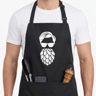 Tablier de cuisine noir avec illustration blanche d'une barbe houblon, lunettes de soleil et coiffure vintage.