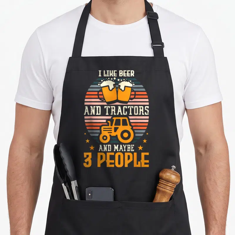 Tablier de cuisine noir avec deux verres de bière et un tracteur orange sous le texte « I like beer and tractors ».