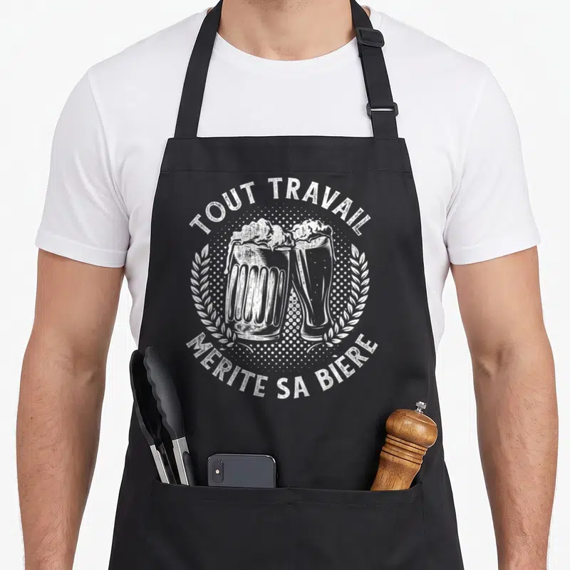Tablier de cuisine noir avec une illustration blanche de deux verres de bière et le texte Tout travail mérite sa bière.