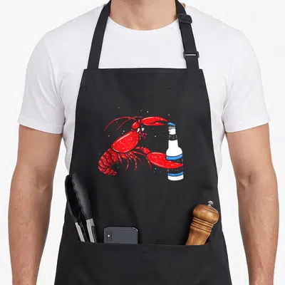 Tablier de cuisine noir avec illustration d'une écrevisse rouge tenant une bouteille blanche à bandes bleues.