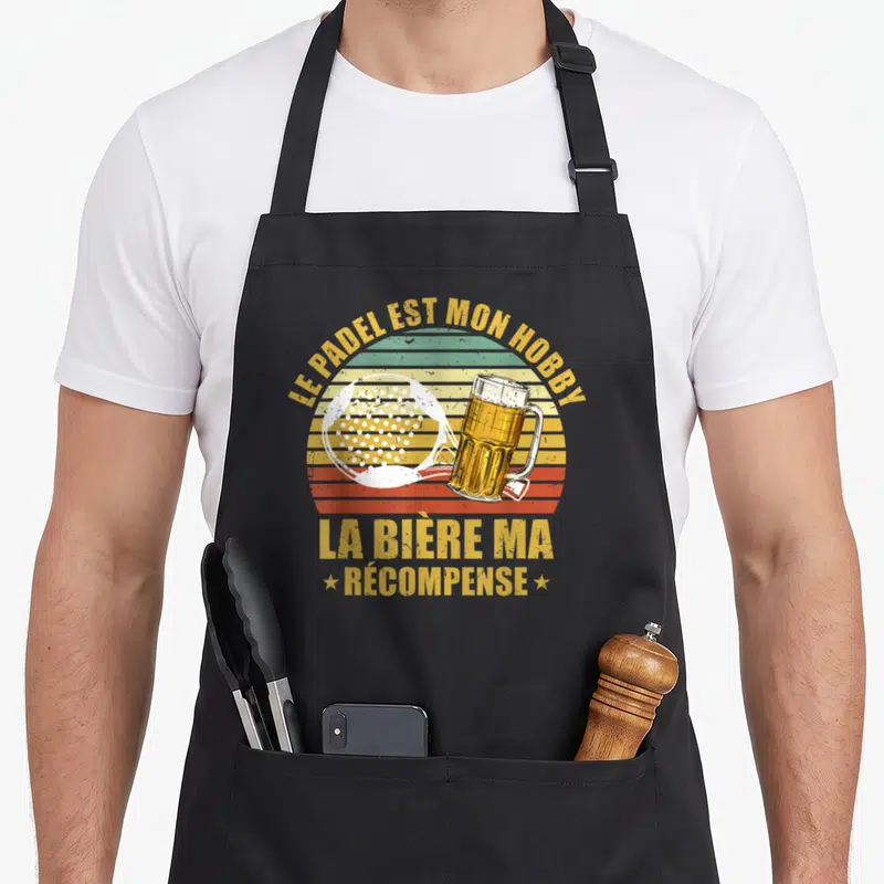 Tablier de cuisine noir avec raquette de padel et verre de bière sur fond rayé coloré retro.