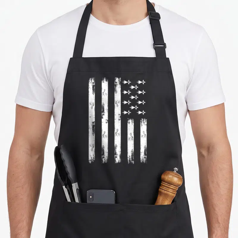 Tablier de cuisine noir avec drapeau breton blanc texturé et inscription vintage sur le devant.