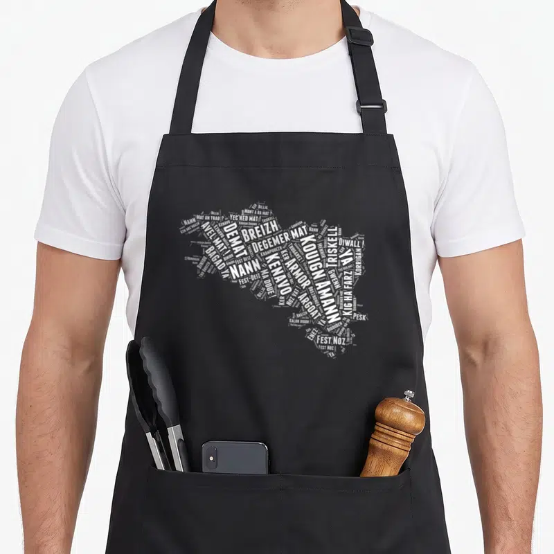 Tablier de cuisine noir avec une carte de Bretagne formée par un nuage de mots bretons en blanc comme Breizh ou Fest Noz.