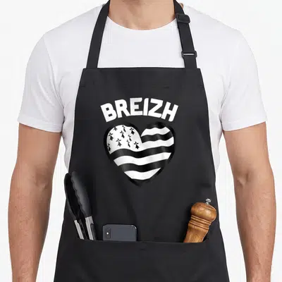 Tablier de cuisine noir avec un cœur stylisé aux rayures et ermines portant le mot BREIZH en lettres blanches.