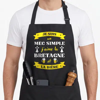 Tablier de cuisine noir avec inscription jaune et blanche sur la Bretagne et la bière, orné de deux verres et de symboles floraux.