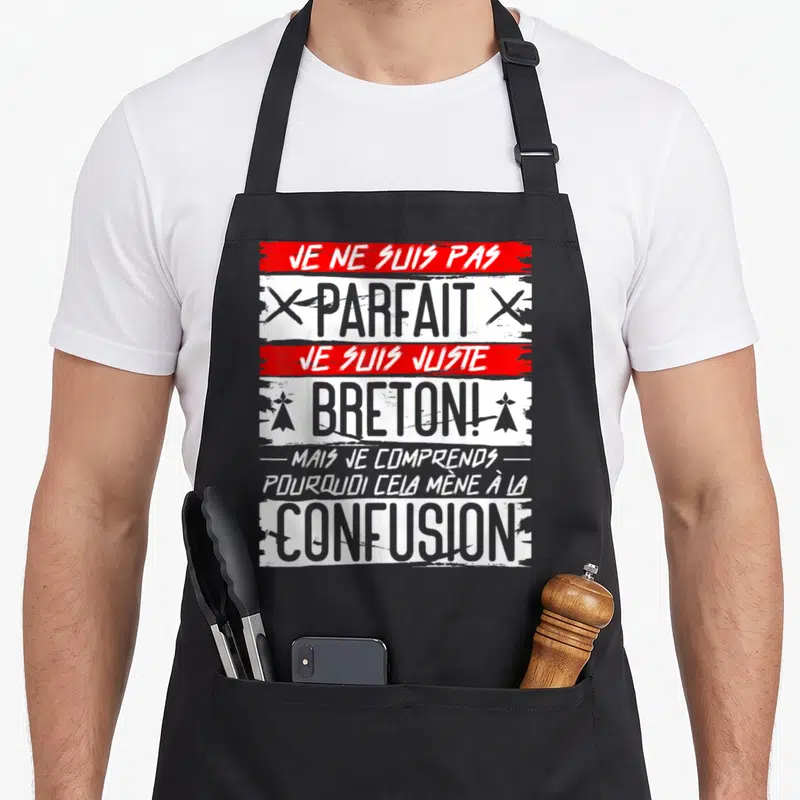 Tablier de cuisine noir avec inscription Je ne suis pas parfait je suis juste Breton en typographie grise et rouge.