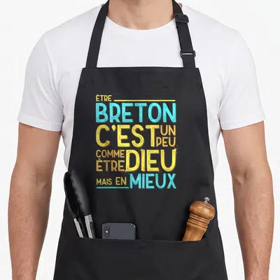 Tablier de cuisine noir avec un slogan humoristique sur la Bretagne en lettres bleues et jaunes stylisées.