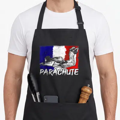 Tablier de cuisine noir avec illustration de parachutiste sur fond tricolore et le mot PARACHUTE en bas.
