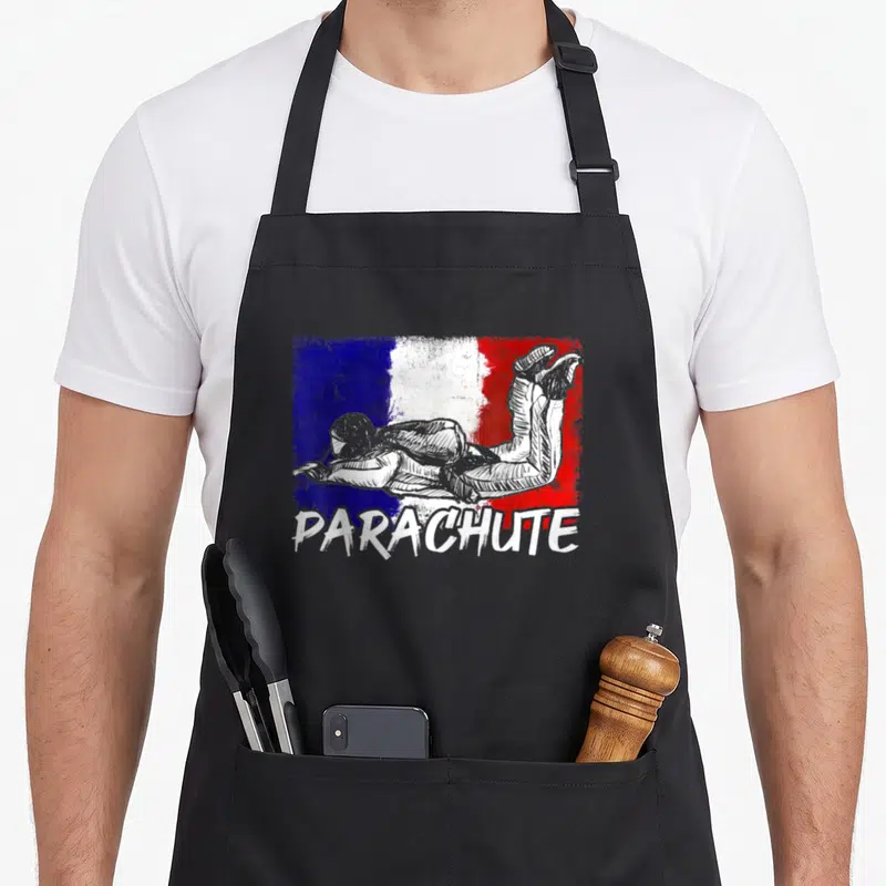 Tablier de cuisine noir avec illustration de parachutiste sur fond tricolore et le mot PARACHUTE en bas.