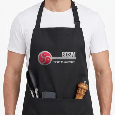 Tablier de cuisine noir avec logo BDSM triskel rouge et texte The Key to a Happy Life en gris.