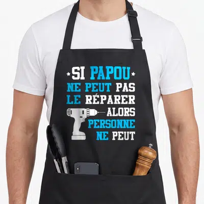 Tablier de cuisine noir avec texte blanc et bleu et une illustration de perceuse électrique blanche.