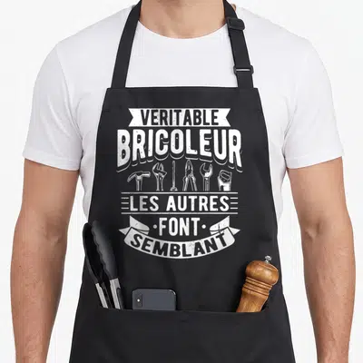 Tablier de cuisine noir avec inscription véritable bricoleur et illustrations d'outils comme un marteau et une pince.