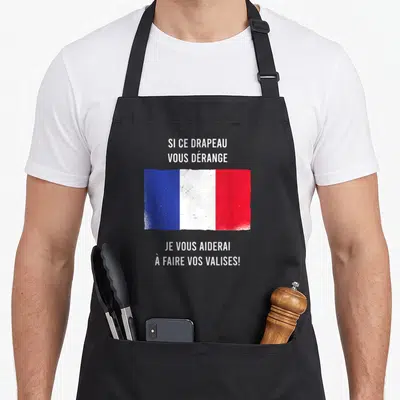 Tablier de cuisine noir avec drapeau français usé et texte humoristique sur fond gris uni