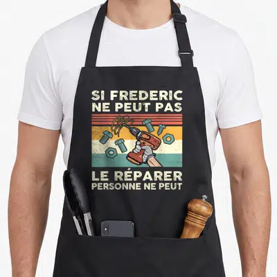 Tablier de cuisine noir avec une illustration vintage d'une perceuse orange et des vis bleues sur fond rayé coloré.