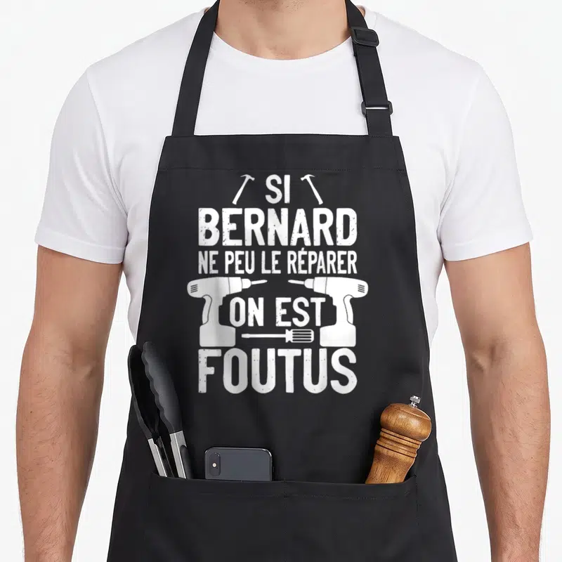 Tablier de cuisine noir avec inscription blanche « Si Bernard ne peut le réparer on est foutus » et illustrations d'outils.